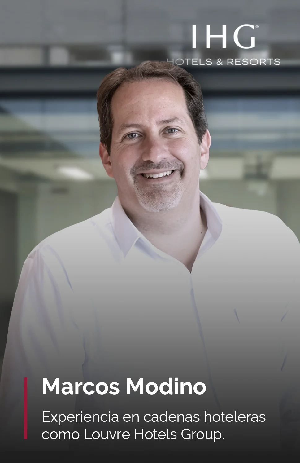 Retrato de Marcos Modino, con experiencia en cadenas hoteleras como Louvre Hotels Group, profesor del MBA en Dirección de Hoteles, sonriendo mientras viste una camisa blanca. En el fondo, se aprecia un entorno corporativo con el logo de IHG Hotels & Resorts.