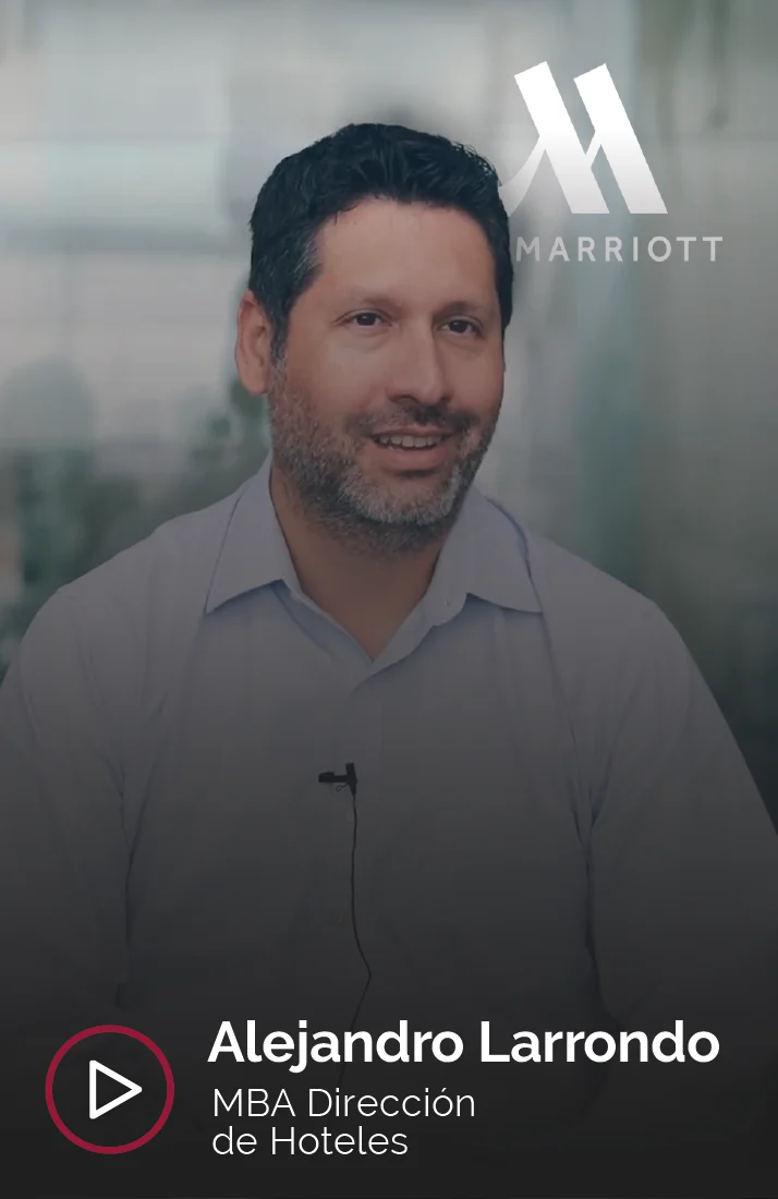 Alejandro Larrondo, profesional del sector hotelero y graduado del MBA en Dirección de Hoteles, aparece en la imagen sentado y sonriendo mientras es entrevistado. Al fondo se observa el logo de Marriott, donde actualmente trabaja, lo que refleja su éxito en el campo de la administración hotelera. Lleva una camisa clara y un micrófono de solapa.