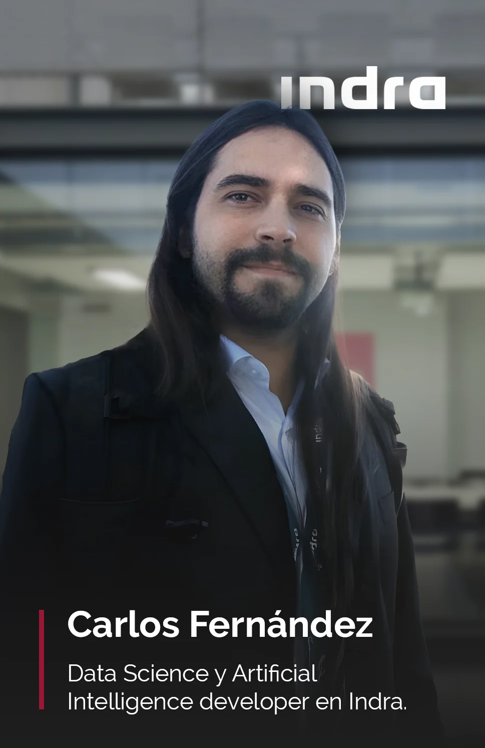 Retrato de Carlos Fernández, Data Science y Artificial Intelligence developer en Indra, profesor del Master en Business Analytics. Aparece con una chaqueta oscura y camisa blanca, en un entorno corporativo moderno. En la esquina superior derecha se ve el logotipo de Indra.