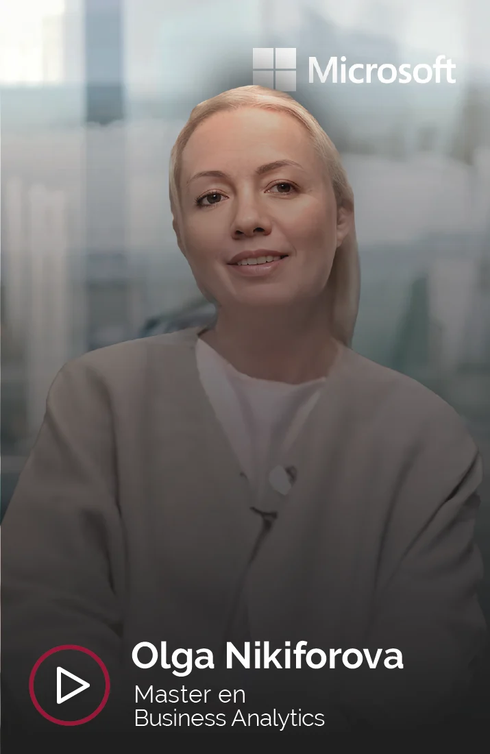 Olga Nikiforova, alumna del Master en Business Analytics, sonriendo durante una entrevista para Esden Business School. Olga viste una chaqueta de tonos neutros y está frente a un fondo de oficina moderna, con luz natural filtrada a través de paredes de cristal. El logotipo de Microsoft se encuentra en la esquina superior derecha, indicando su conexión profesional con la empresa. La imagen transmite una sensación de confianza y profesionalismo.