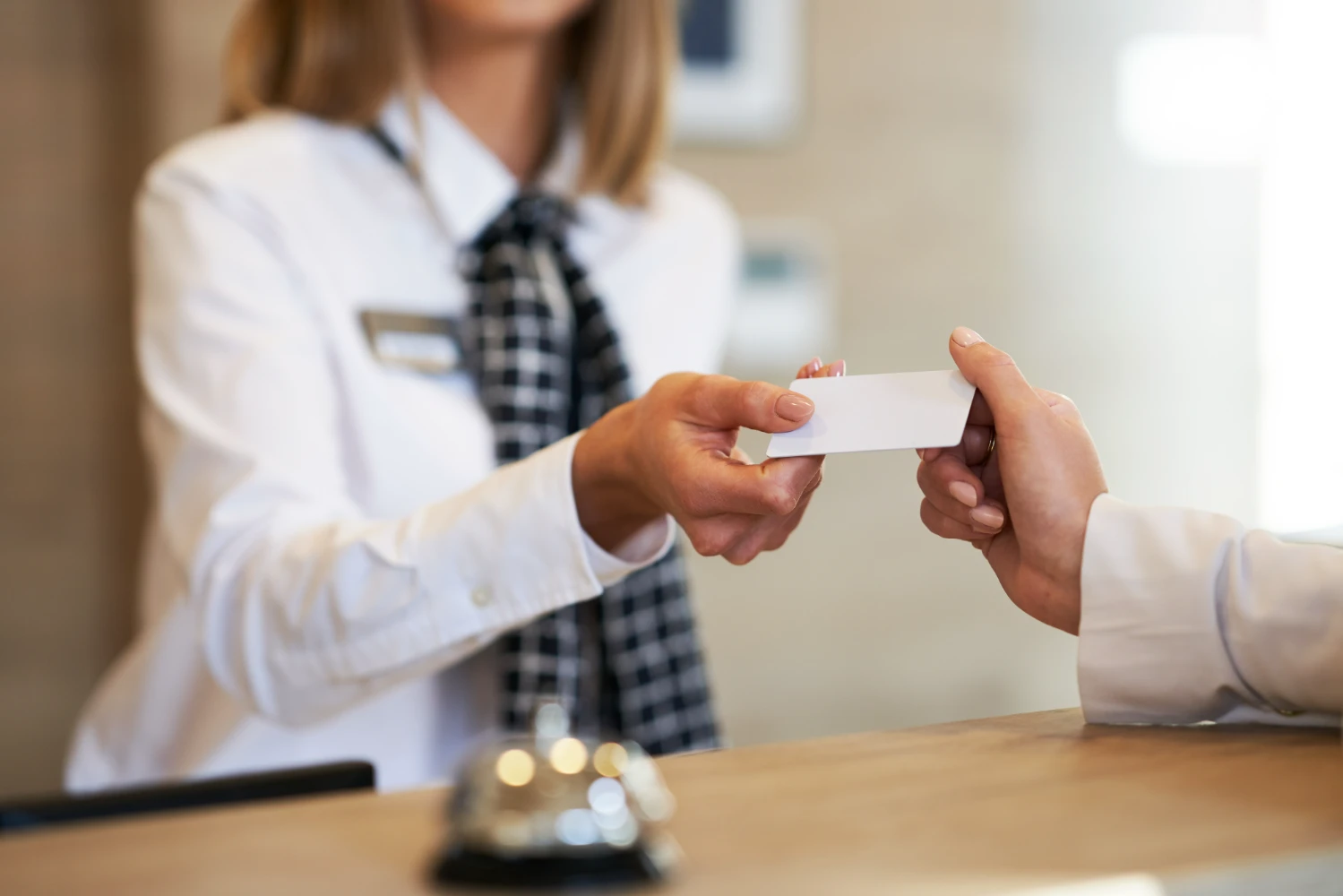 Recepcionista entregando llave de habitación en hotel, representando el récord de ocupación en hoteles españoles en agosto.